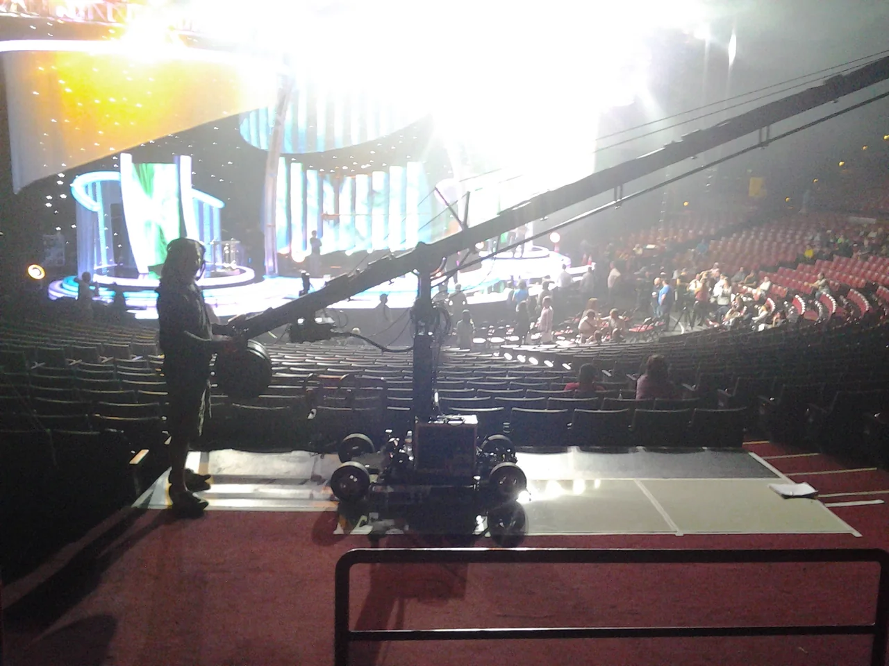 Camera crane silhouetted against a live entertainment stage