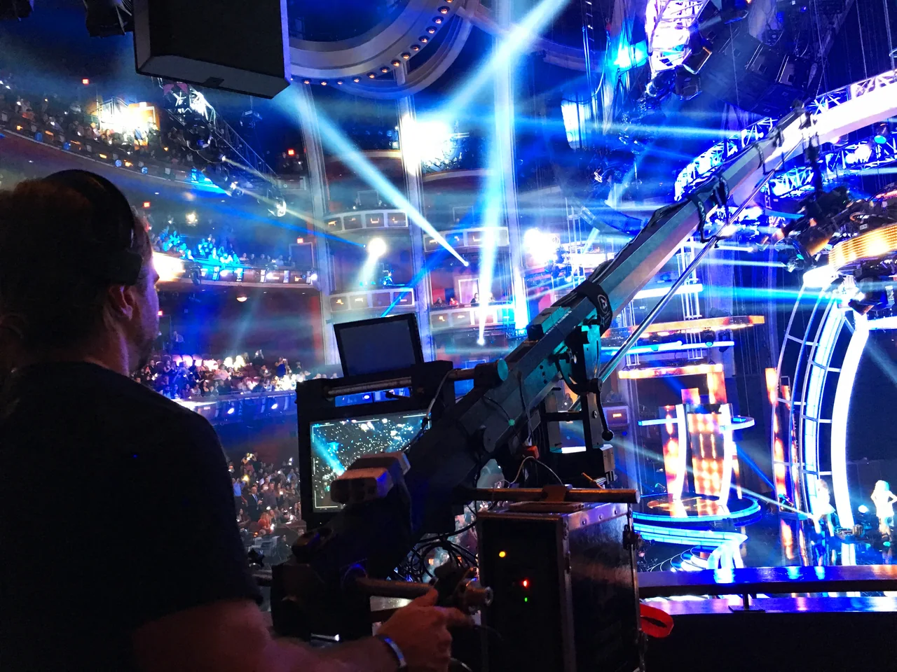 Ariel at the crane controls overlooking a brightly lit television stage